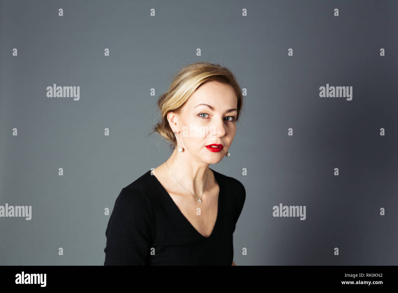 Portrait of beautiful woman in a black dress against grey background ...