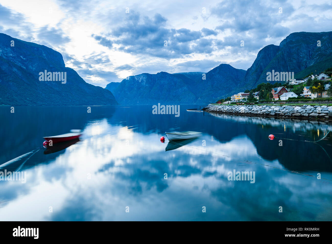Village and mountains reflected on fjord at dusk, Aurland, Norway, Europe Stock Photo