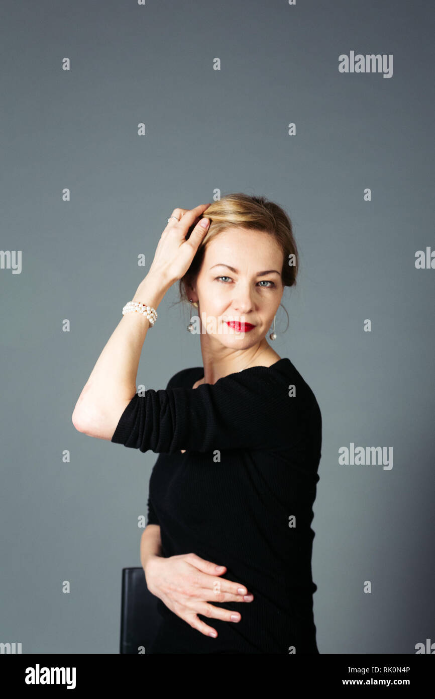 Portrait of beautiful woman in a black dress against grey background Stock Photo