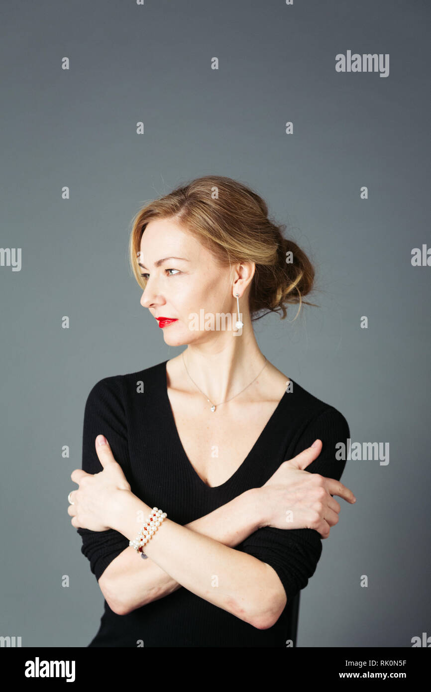 Portrait of beautiful woman in a black dress against grey background ...