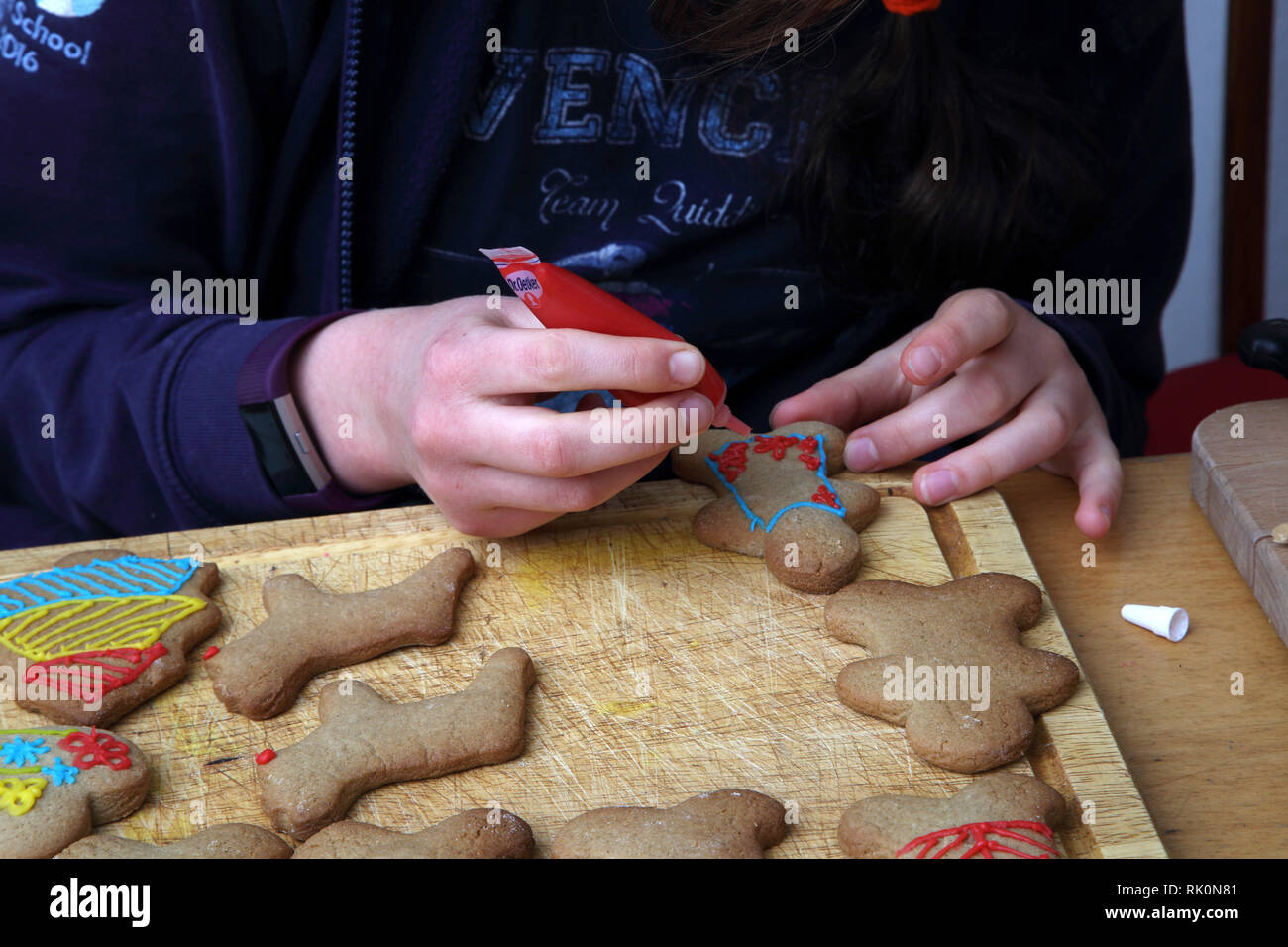 Thirteen Year Old Girl Decorating Christmas Cookies with Red Icing Surrey England Stock Photo