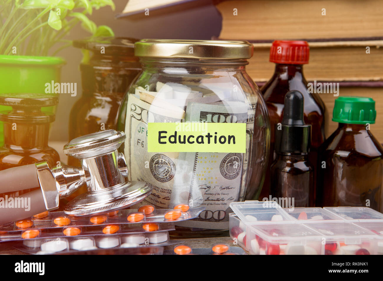 Medical education concept - money glass, books, pharmacy bottles Stock Photo