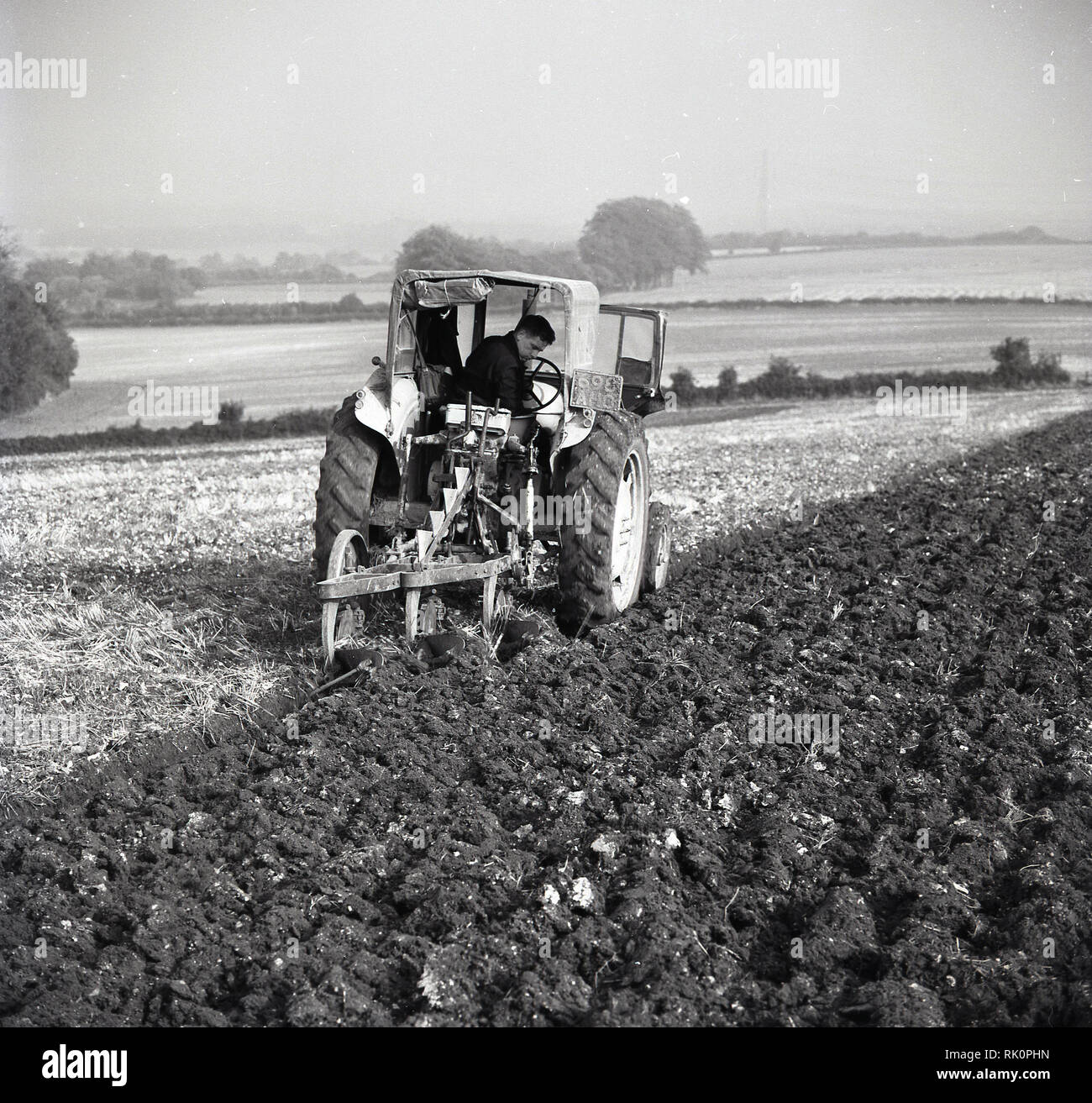 1950s, agriculture, a farmer on a tractor carefully ploughing a field, England, UK. Stock Photo