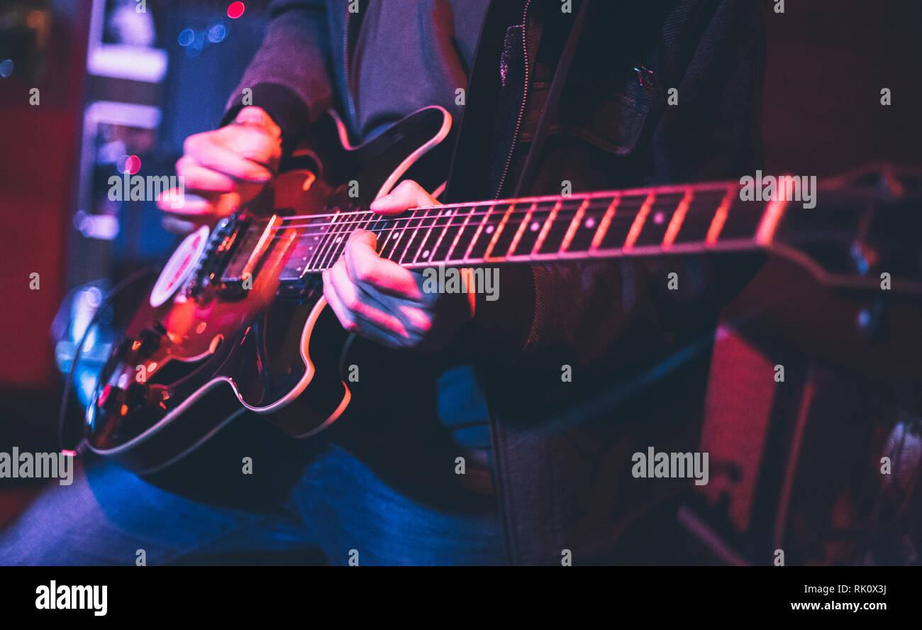 Electric guitar player on a stage with colorful blue and purple scenic illumination Stock Photo