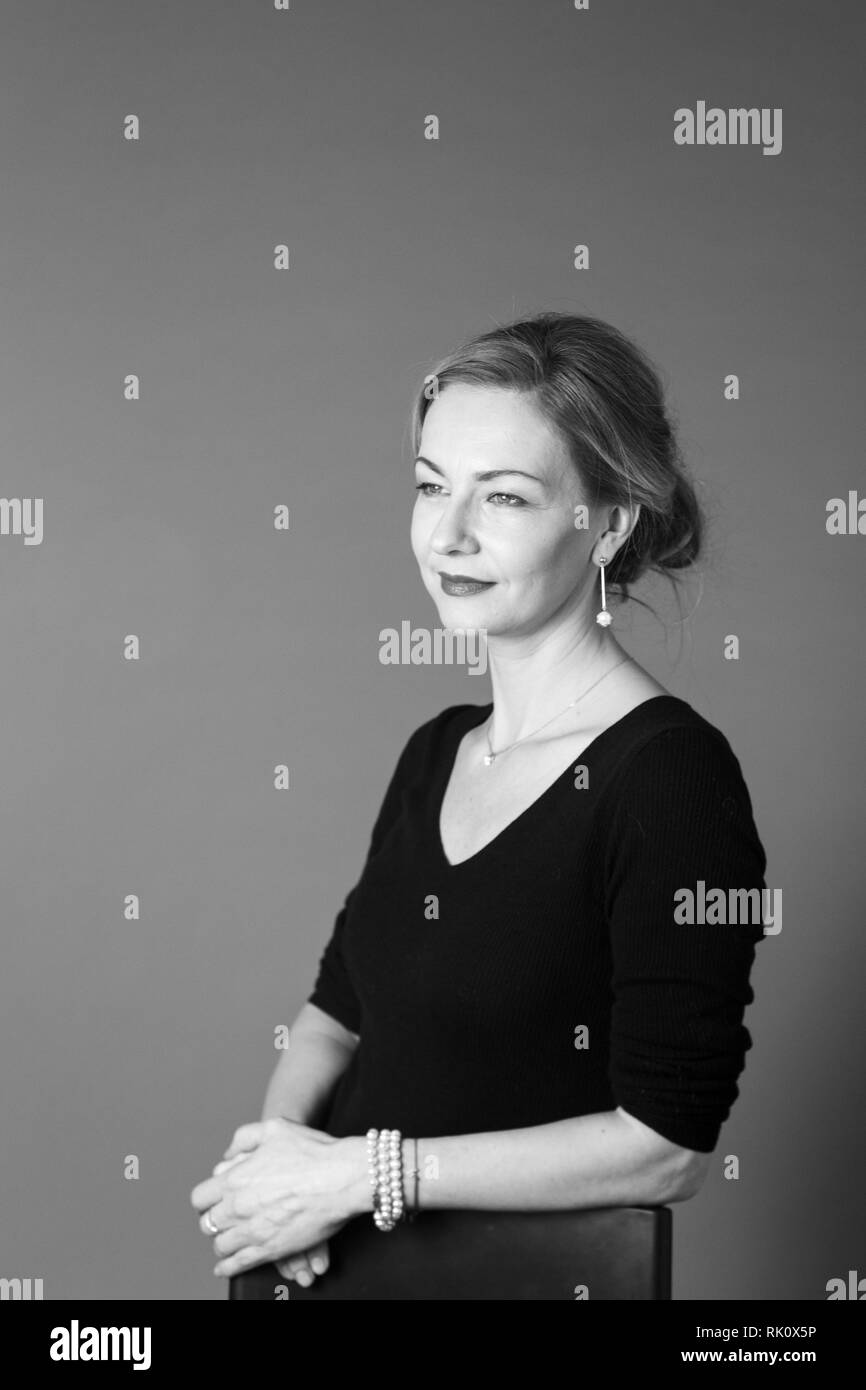 Portrait of beautiful woman in a black dress against grey background ...