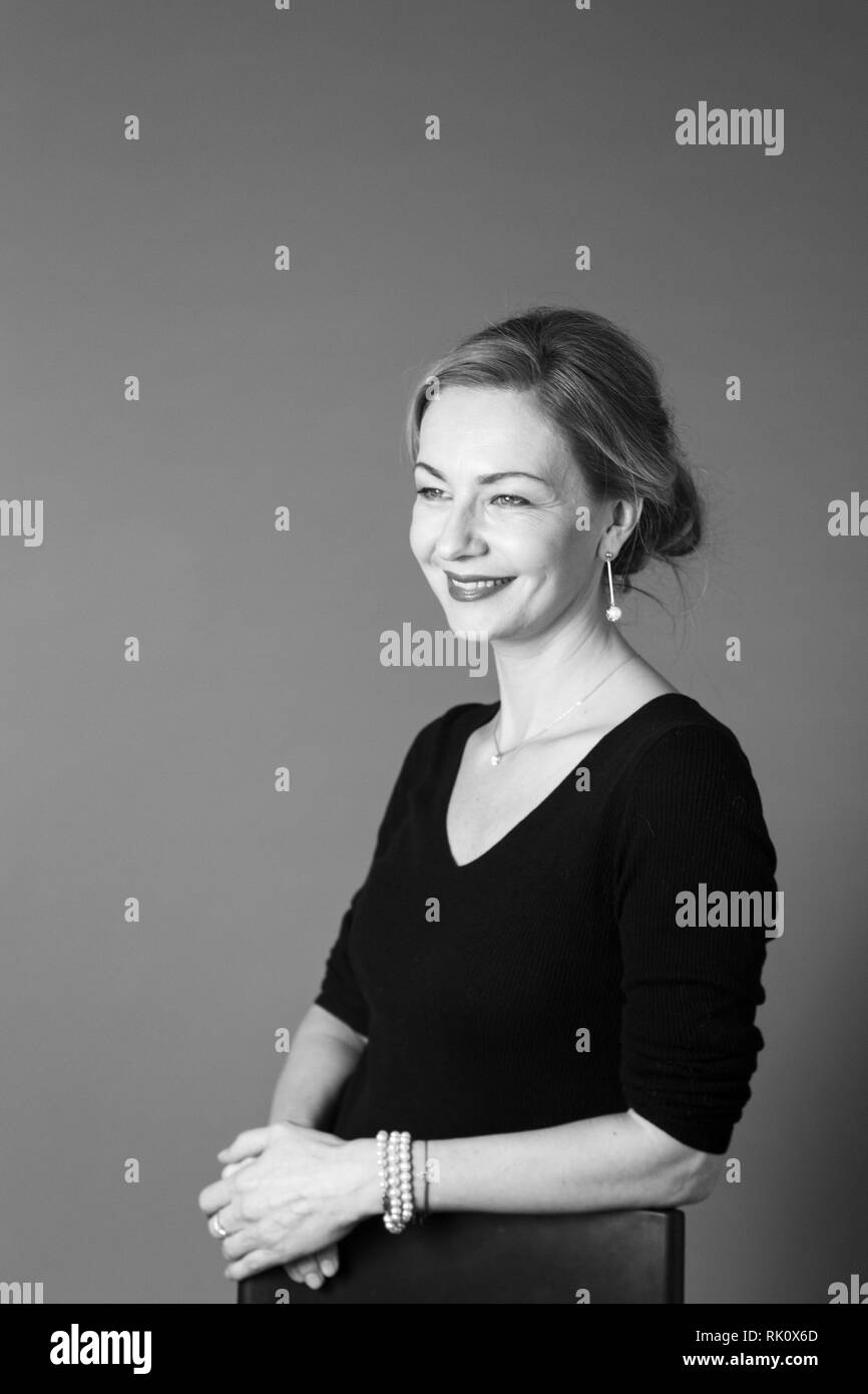 Portrait of beautiful woman in a black dress against grey background ...