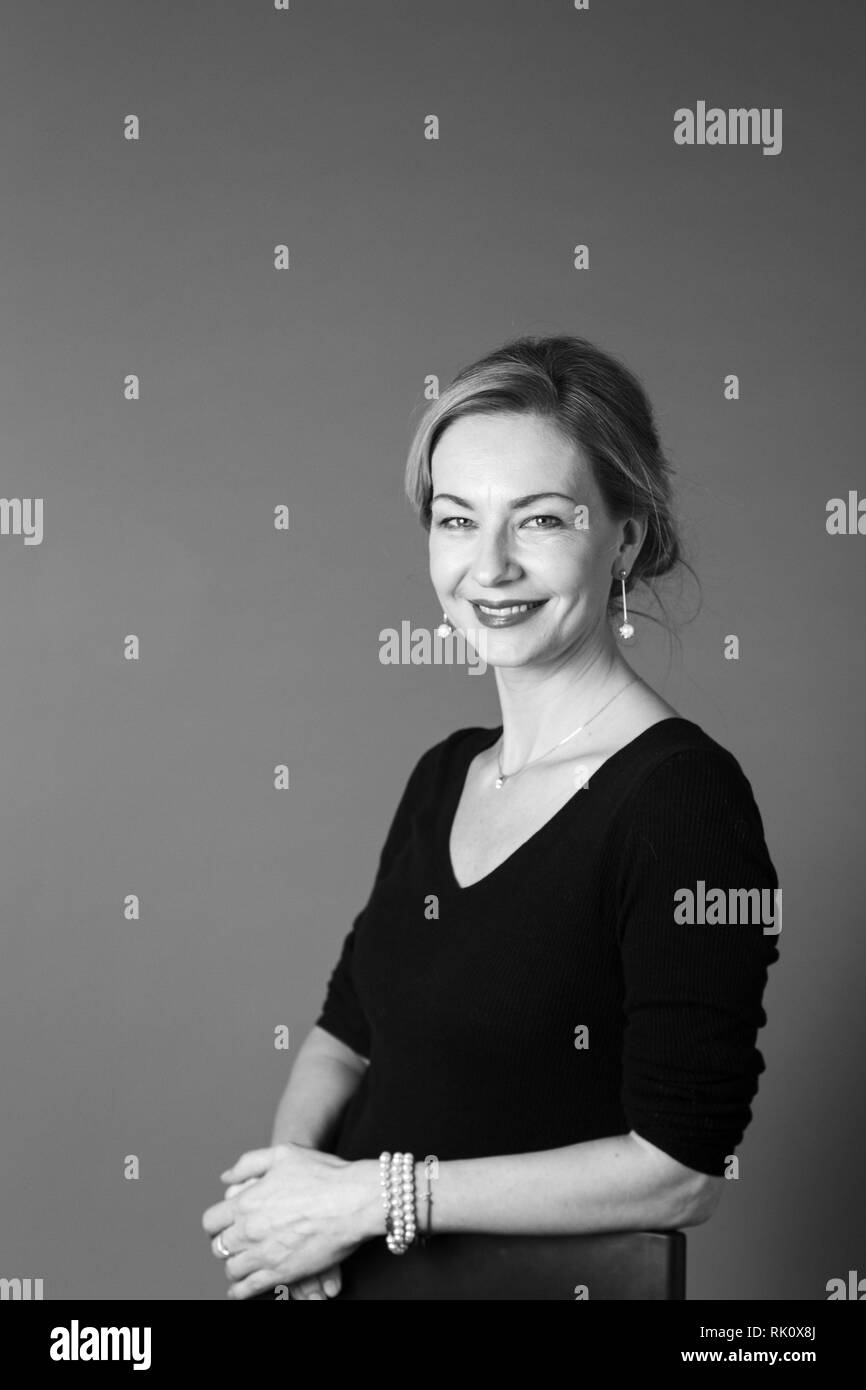 Portrait of beautiful woman in a black dress against grey background ...