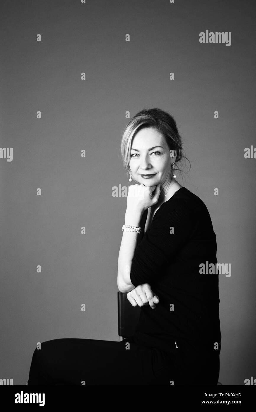 Portrait of beautiful woman in a black dress against grey background ...