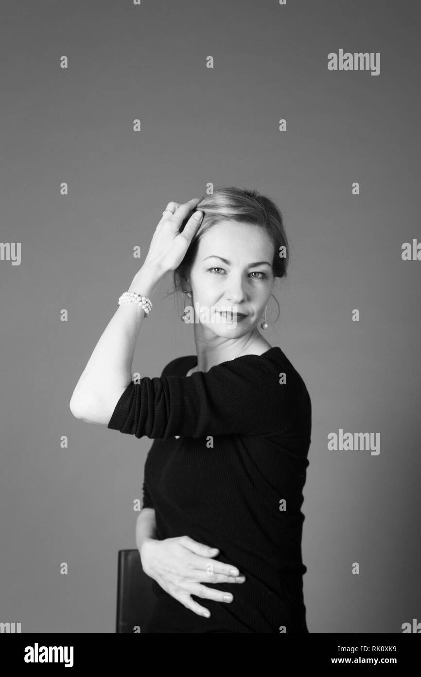 Portrait of beautiful woman in a black dress against grey background ...