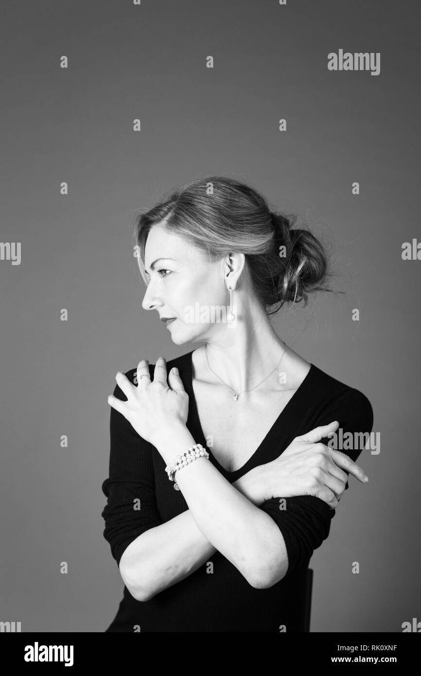 Portrait of beautiful woman in a black dress against grey background ...