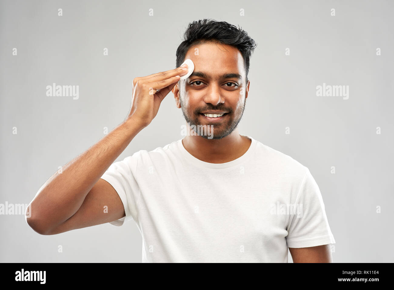smiling indian man cleaning face with cotton pad Stock Photo Alamy