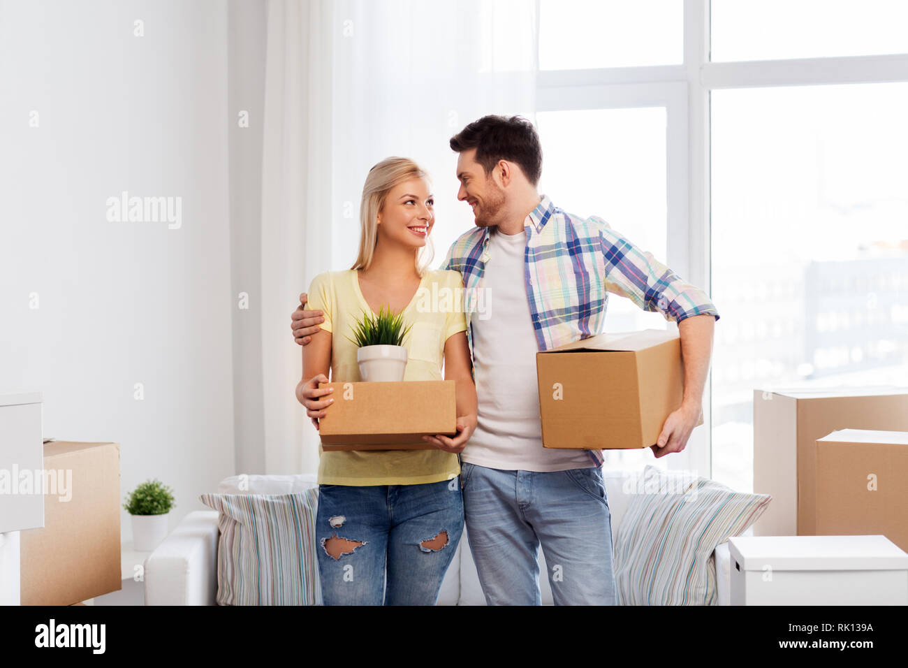 happy couple with boxes moving to new home Stock Photo - Alamy
