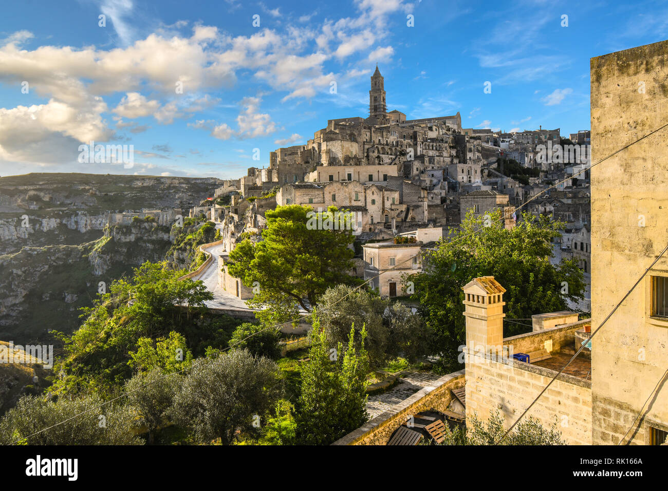 View of the ancient city of Matera, Italy, including the old town, tourist street and mountain path, Sasso Barisano tower and the steep ravine canyon Stock Photo