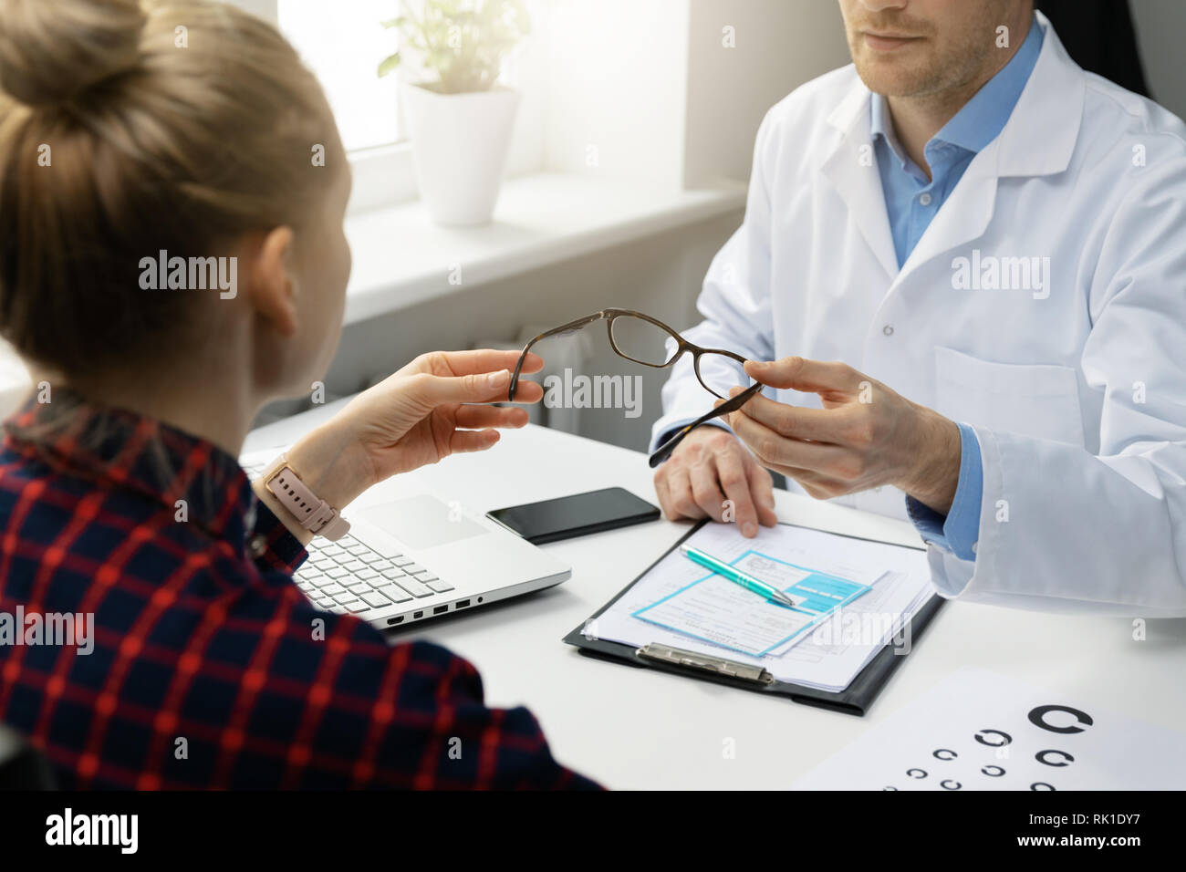 optometrist gives new optical glasses to woman patient Stock Photo