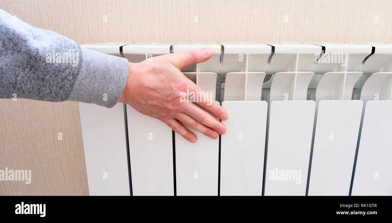 Radiator heating, white radiator in the apartment. Hand felt the