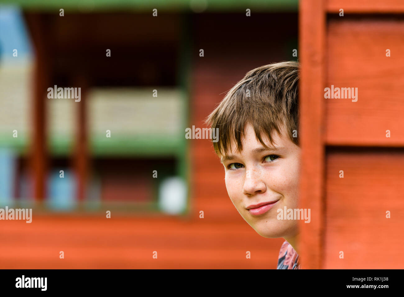 Portrait of young boy looking at camera and smiling by wood cabin, Flam ...