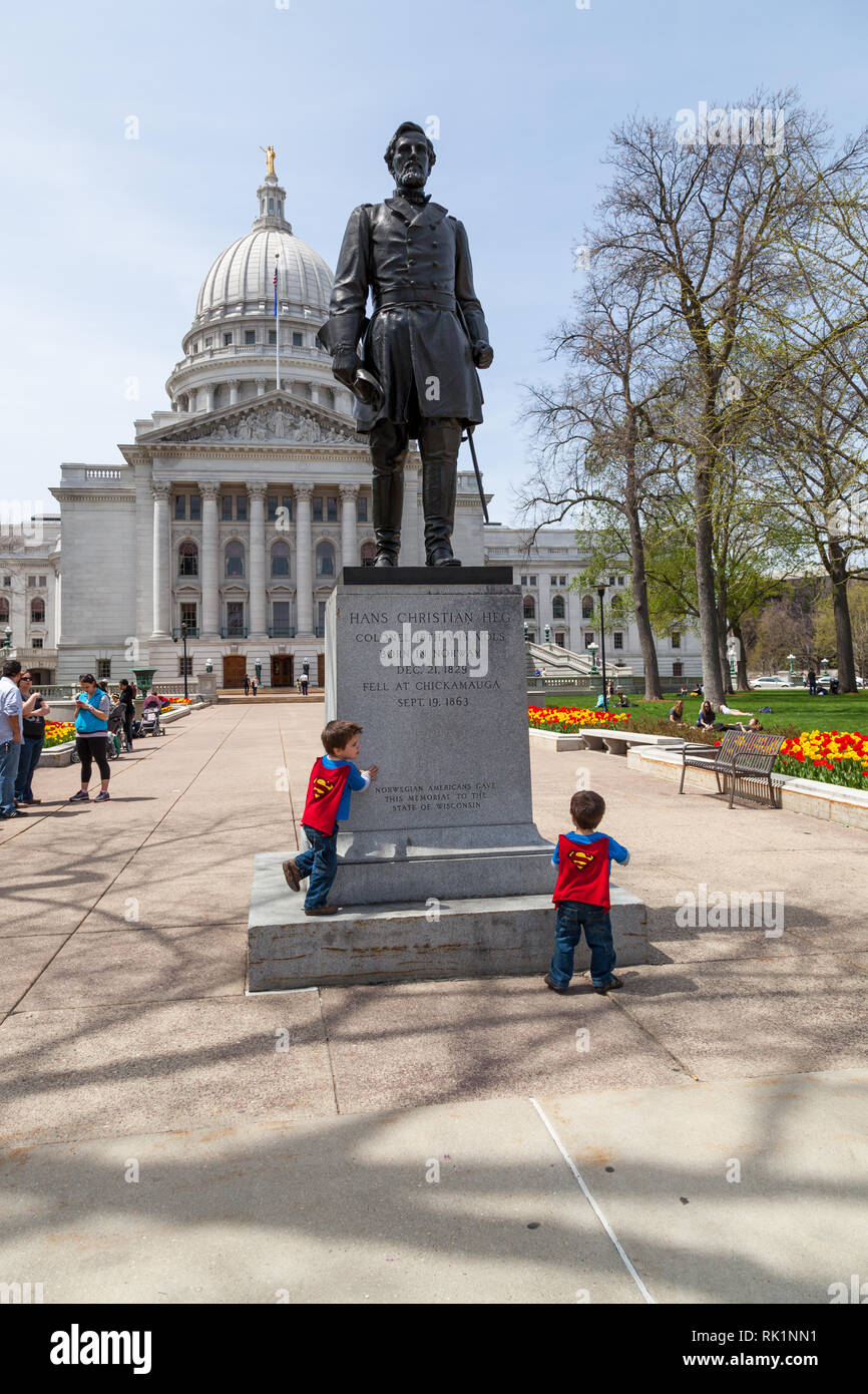 MADISON, WISCONSIN - May 10, 2014: Two small children in Superman capes play in front of a statue of Colonel Hans Christian Heg at the capital buildin Stock Photo