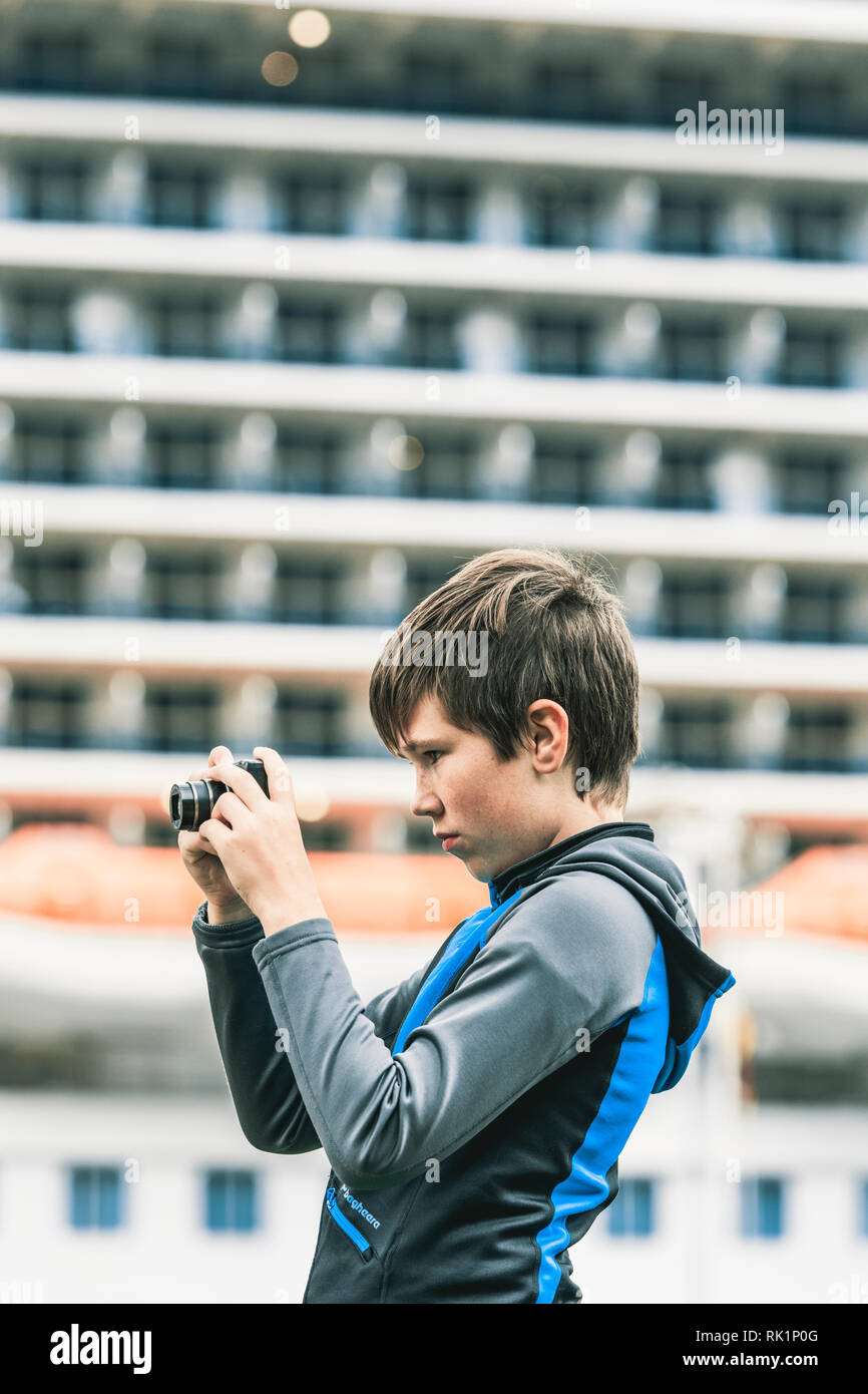 Candid portrait of young boy looking at display screen of digital camera, side view Stock Photo