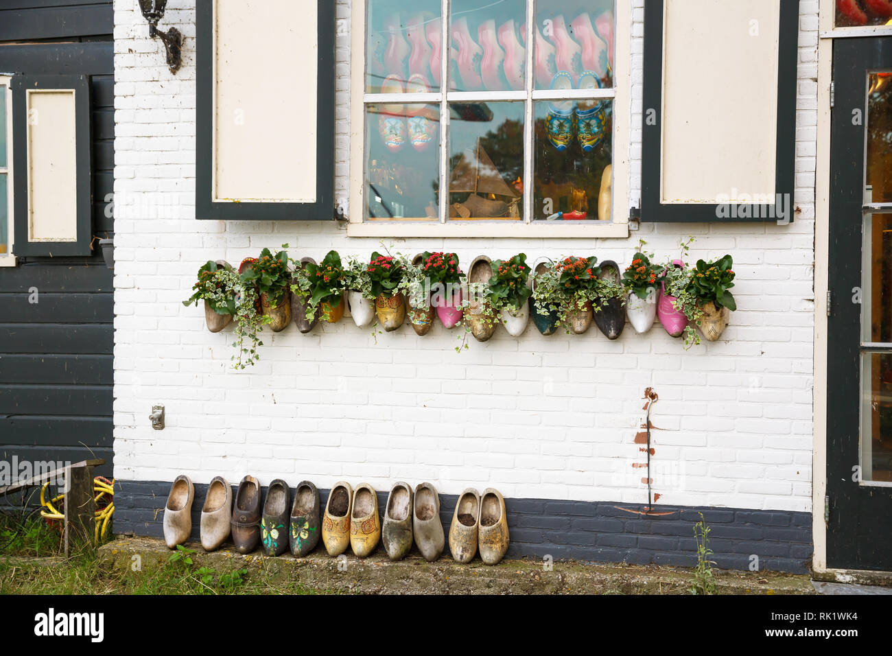 The old traditional wooden clogs with flowers on the white house wall in the Dutch fisherman village Marken. Stock Photo