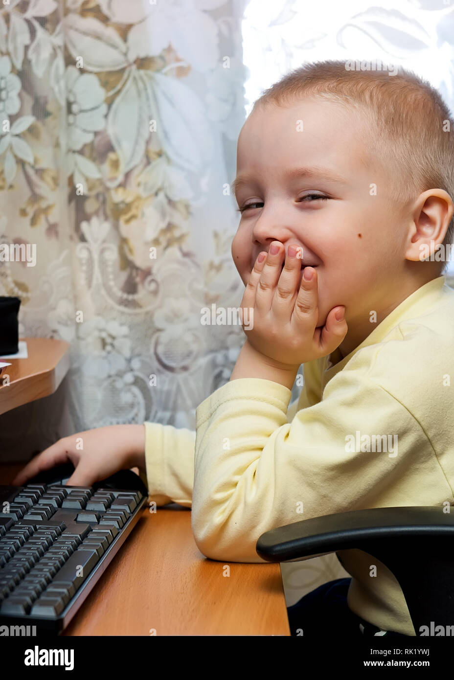 young handsome boy is sitting on chair and working seriously with computer mouse Stock Photo