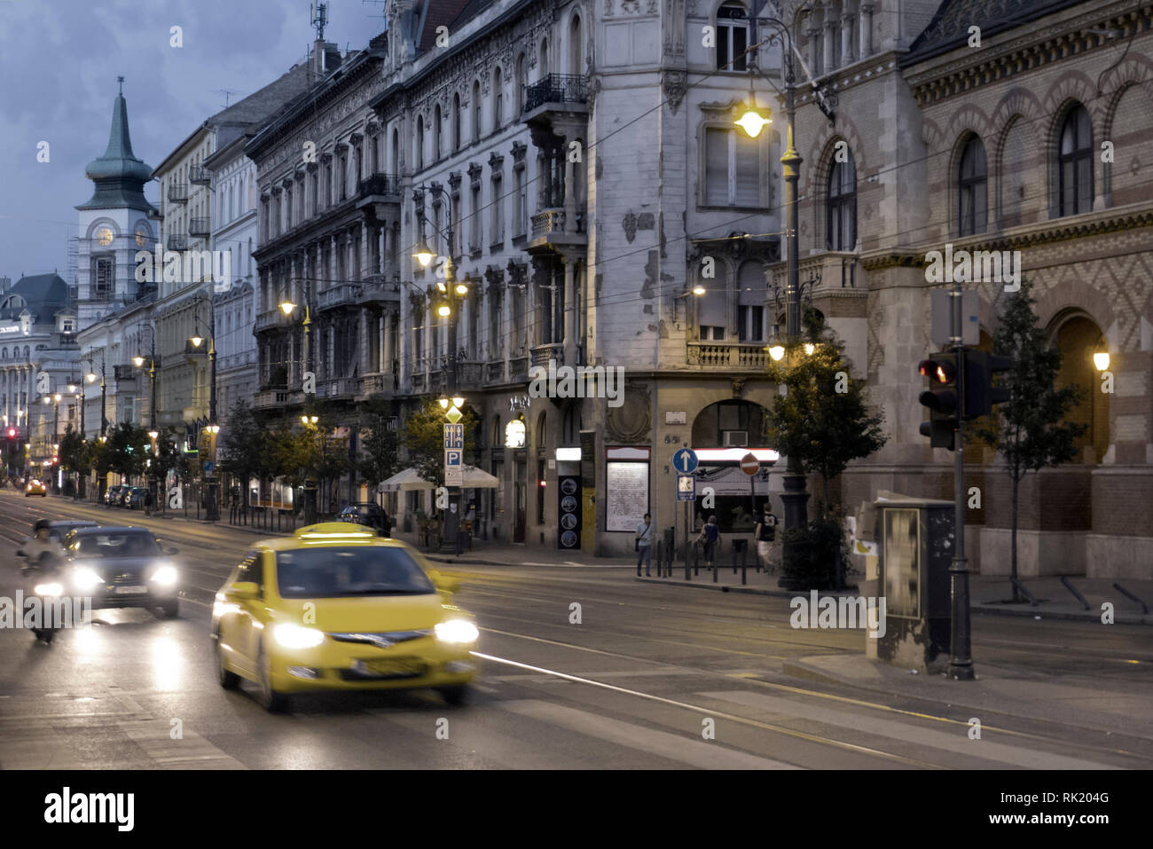 Yellow taxi moving on old city street in dusk Stock Photo