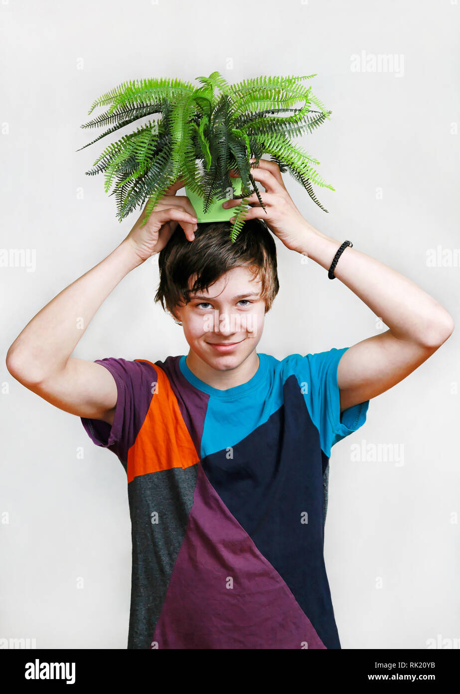 Teenage boy goofing around with plant at head Stock Photo