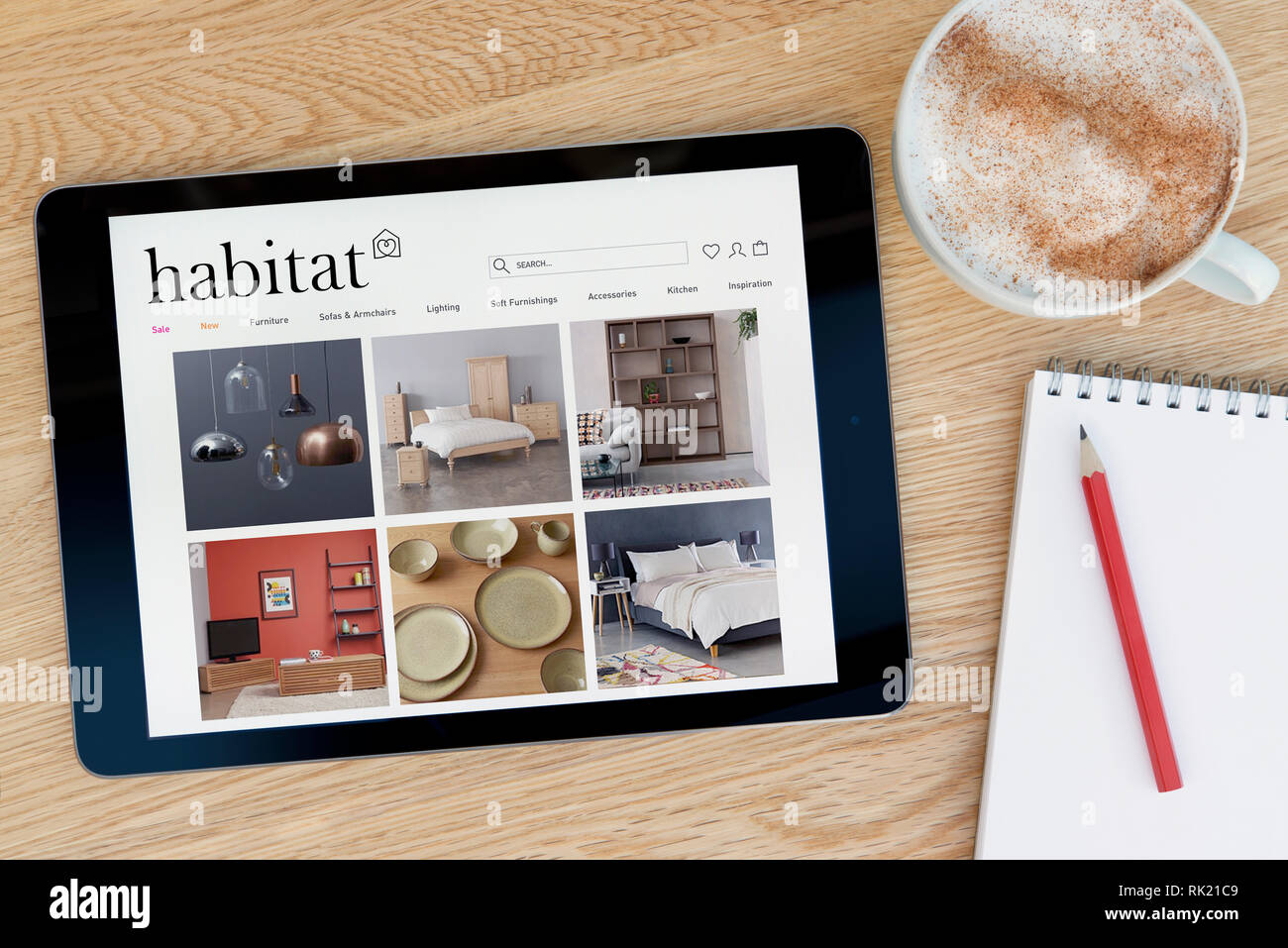 The Habitat website features on an iPad tablet device which rests on a wooden table beside a notepad (Editorial use only). Stock Photo