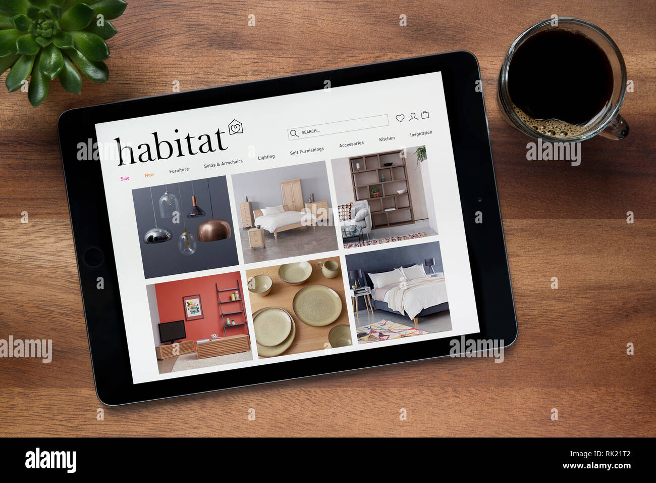 The website of Habitat is seen on an iPad tablet, on a wooden table along with an espresso coffee and a house plant (Editorial use only). Stock Photo