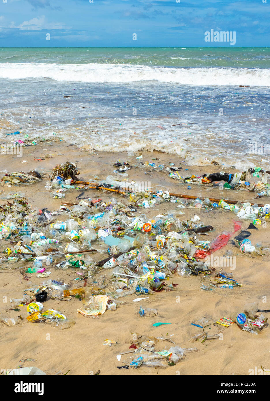 Pollution of plastic bottles, cups, straws and other litter washing up on the beach at Jimbaran Bay, Bali Indonesia. Stock Photo