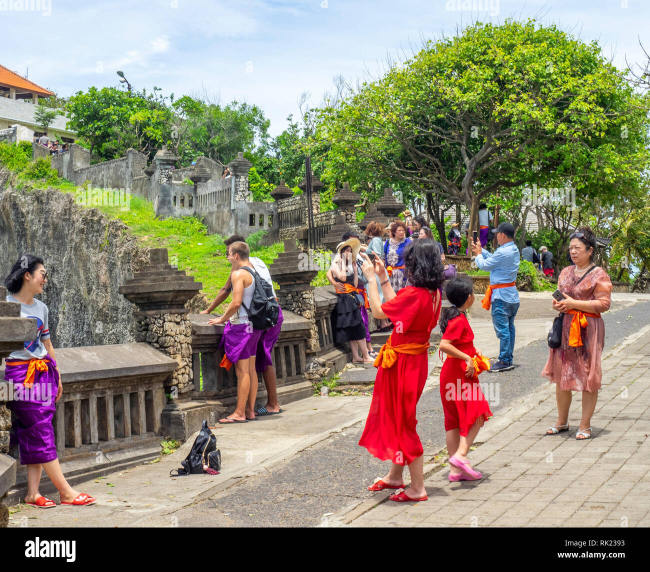 Chinese tourists wearing purple sarongs visiting Uluwatu Temple Bali  Indonesia Stock Photo - Alamy