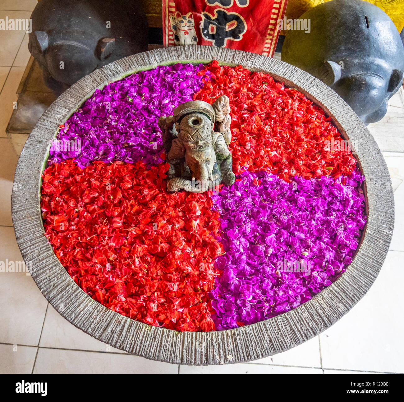 An urn filled with red and magenta flower petals in Jimbaran, Bali Indonesia. Stock Photo