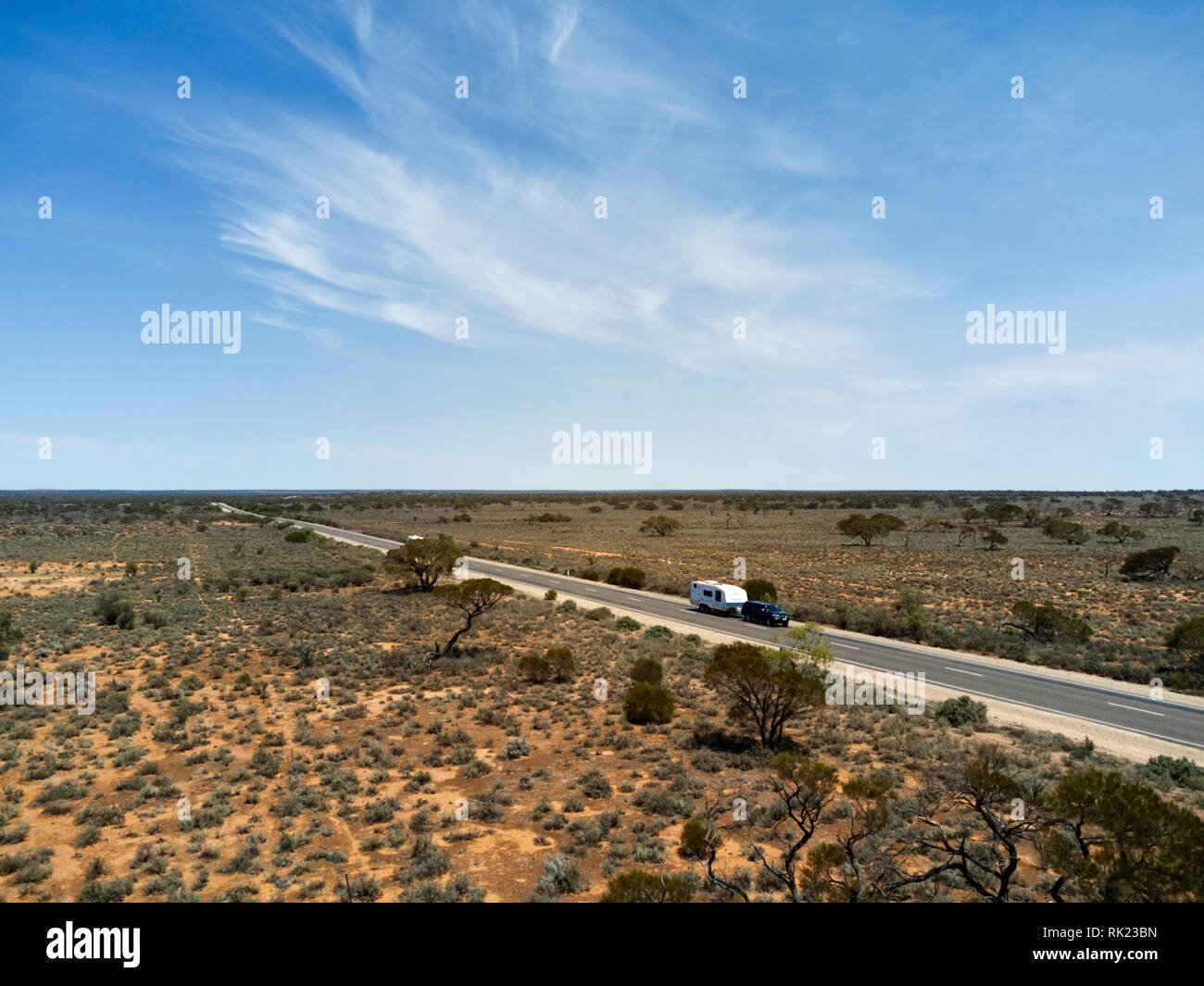 Aerial of a car and caravan travelling along the wide open spaces of the Australian countryside in South Australia. Stock Photo