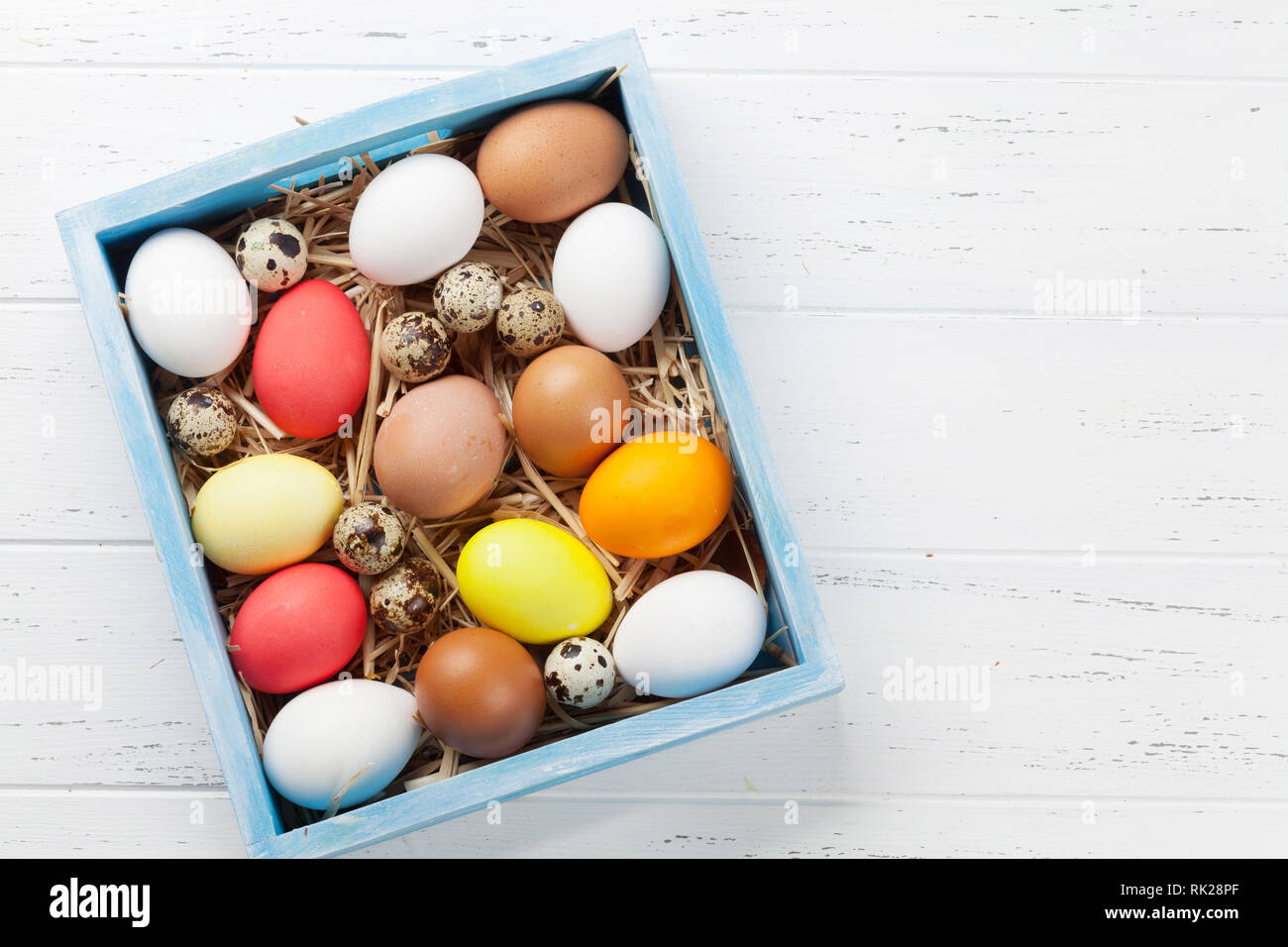 Easter greeting card with colorful eggs in box on white wooden table ...