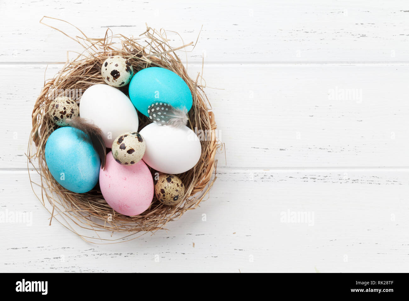 Easter greeting card with colorful eggs in nest on white wooden table ...