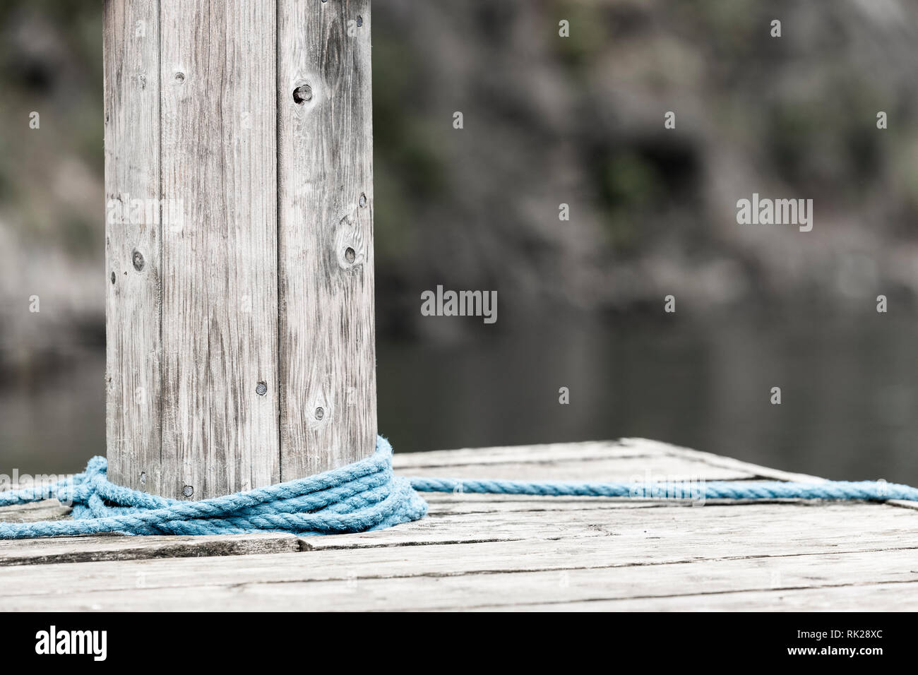 Blue rope wrapped around wooden bollard, close up, cropped Stock Photo