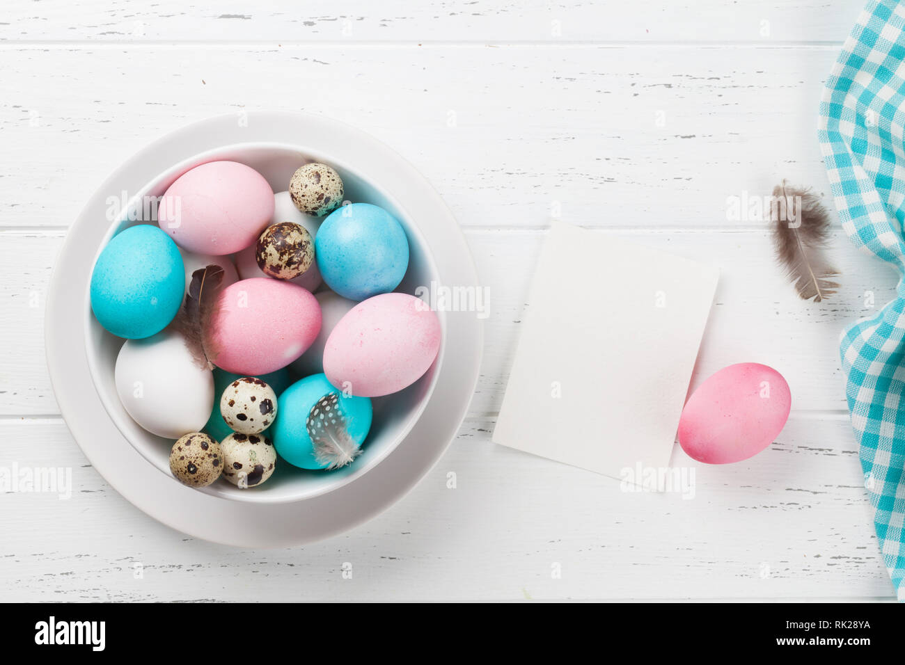 Easter greeting card with colorful eggs in bowl on white wooden table ...