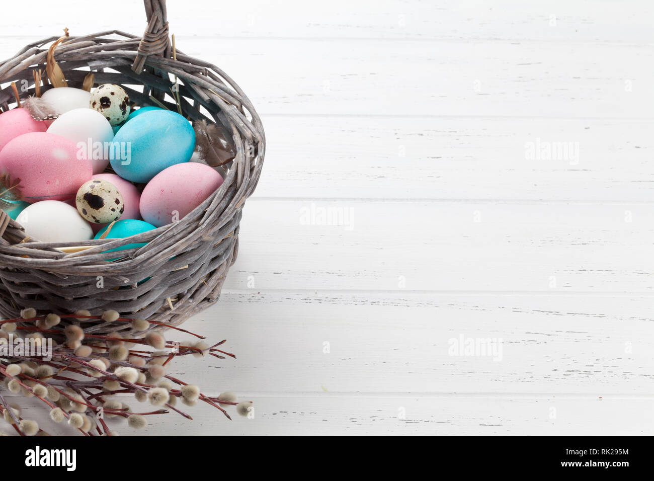 Easter greeting card with colorful eggs in basket on white wooden table ...