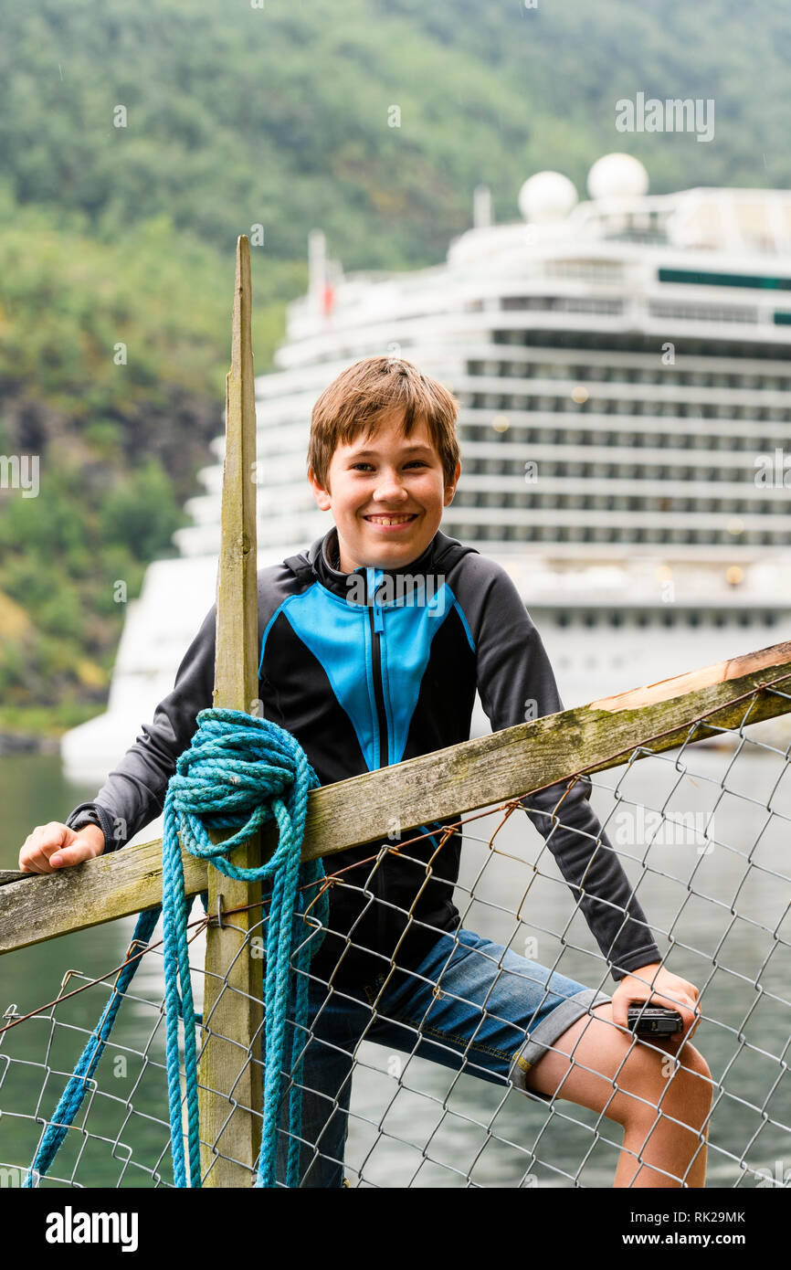 Portrait of cheerful boy standing in front of cruise ship, Flam, Norway, Europe Stock Photo