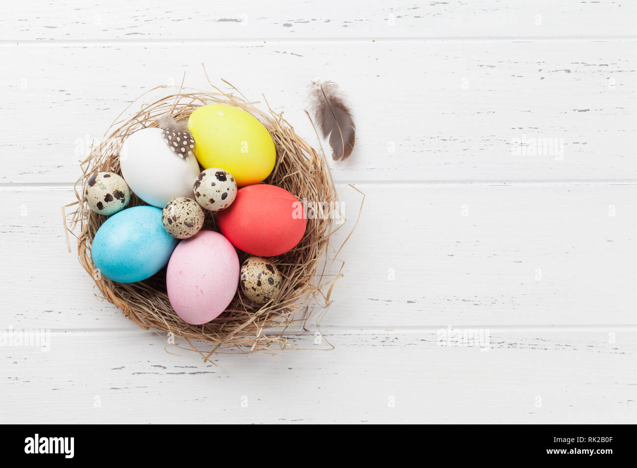 Easter eggs in nest on wooden table. Greeting card backdrop. Top view ...
