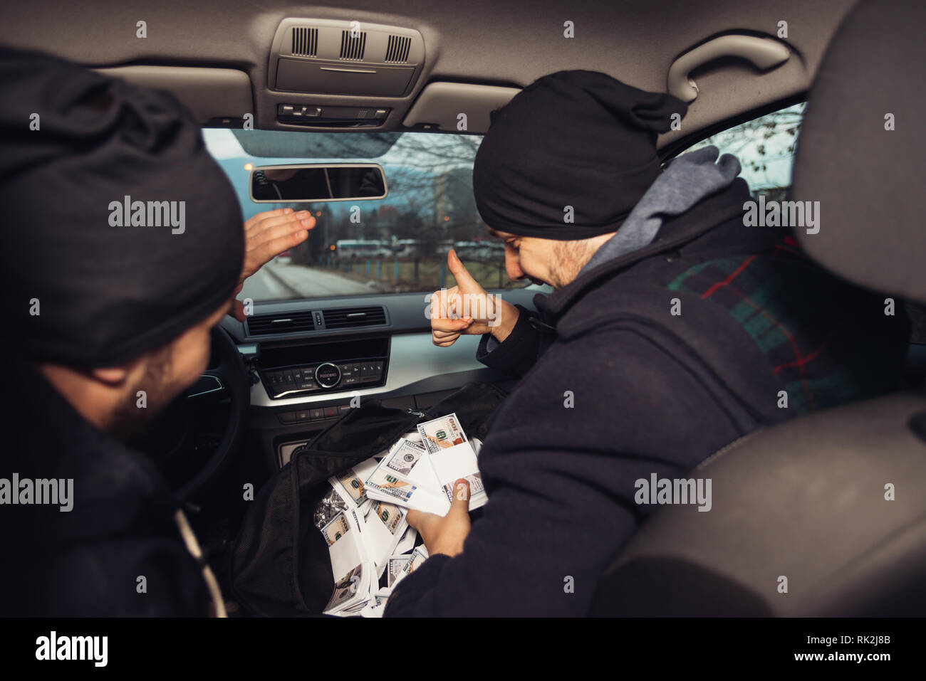 After the successful bank robbery, the thieves are sitting in the car showing off their money and celebrating the win over the law they had. Stock Photo