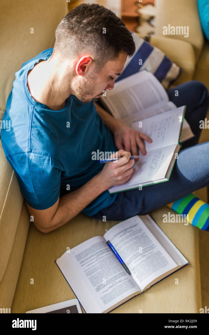 A young man is looking interested while taking notes in the notebook Stock Photo
