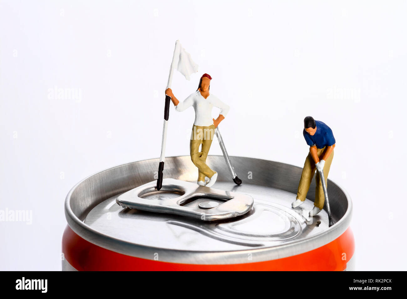 Conceptual diorama image of a miniture figure couple playing golf on a drinks can Stock Photo
