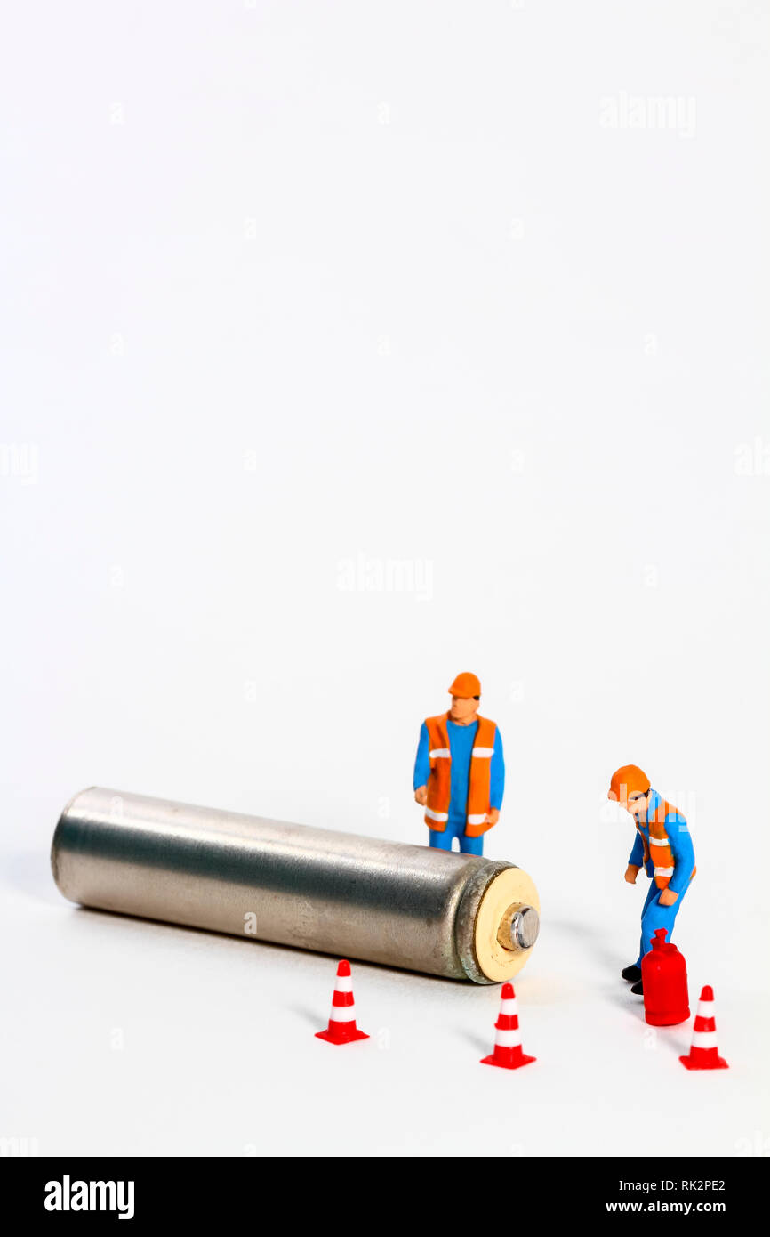 Conceptual diorama image of waste management consisting of miniture figure workmen looking at a battery Stock Photo