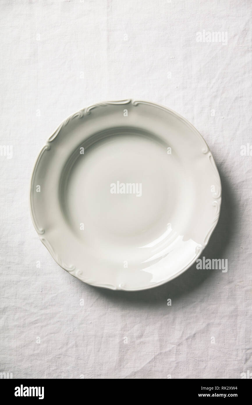 Empty soup plate on white linen tablecloth Stock Photo
