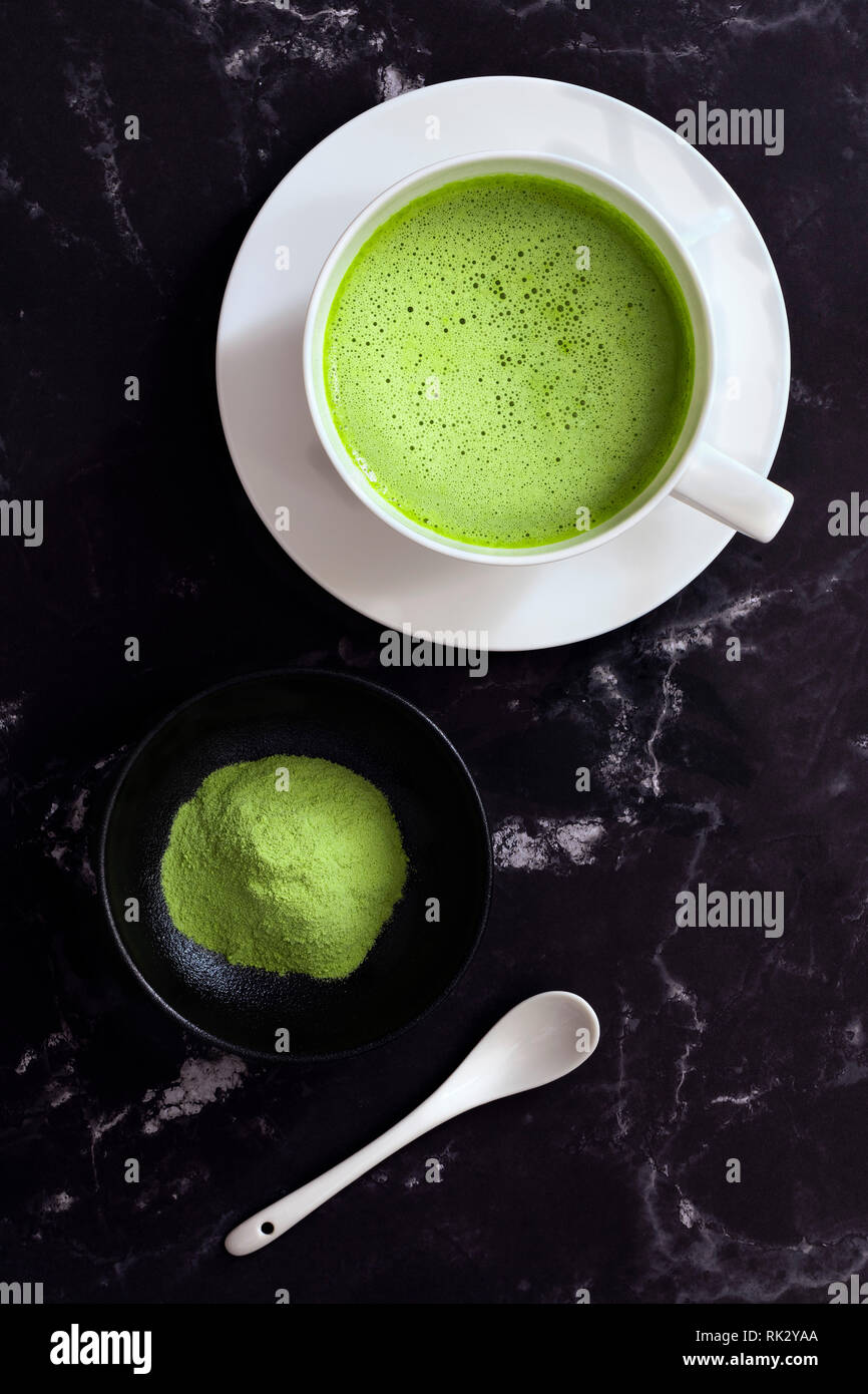A cup of Matcha green tea with a small of bowl of Matcha tea powder and