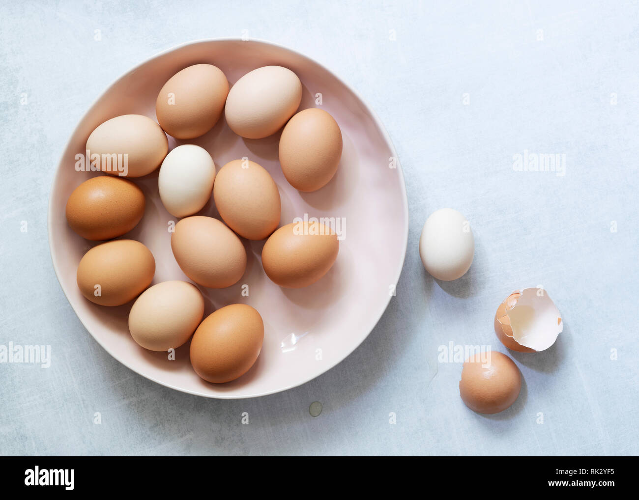 Brown and white eggs in a bowl with egg shells at the side. Stock Photo