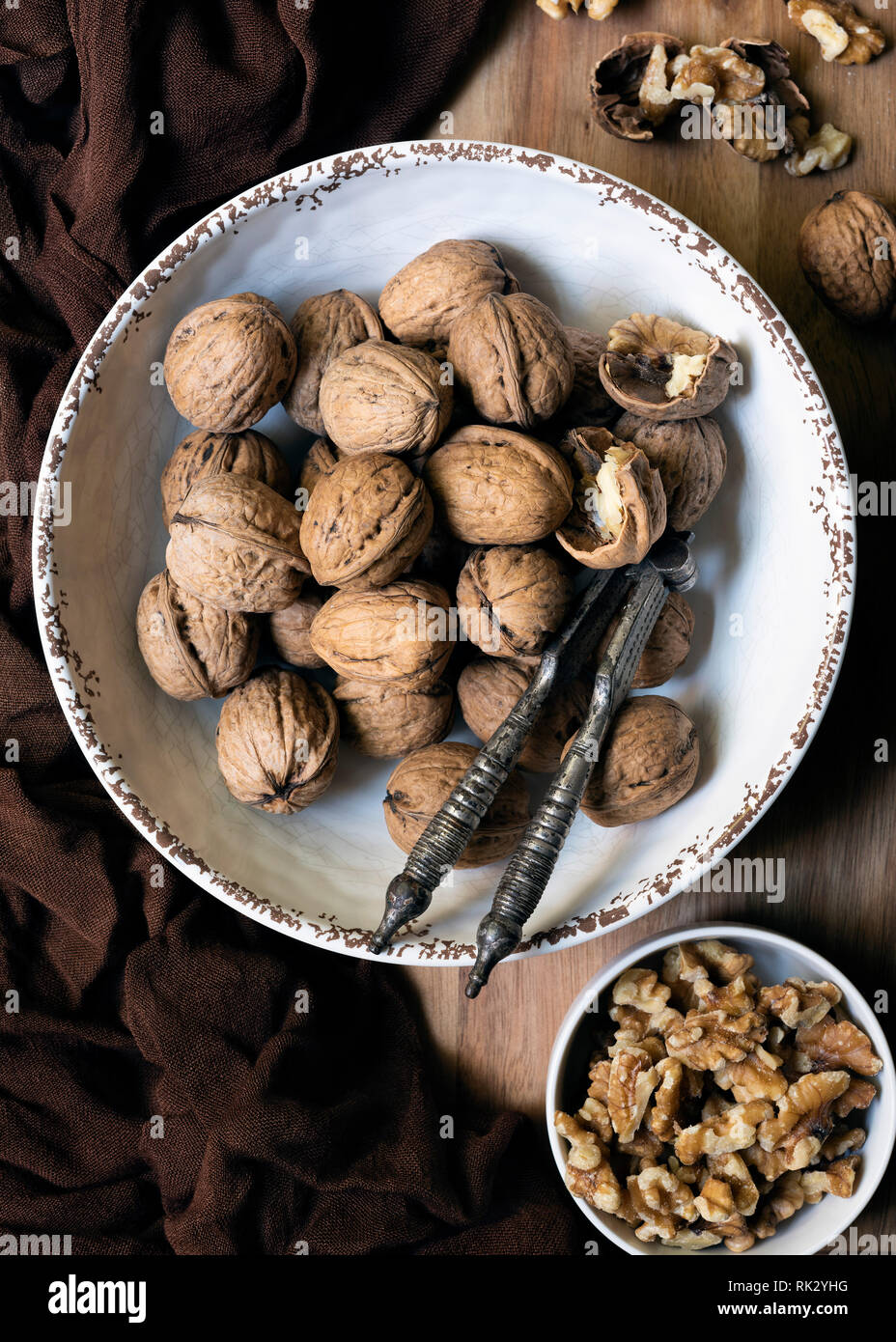 Whole walnuts and walnut pieces in bowls with a vintage nut cracker