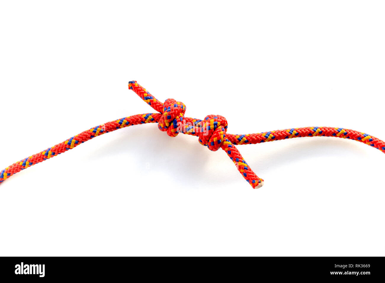 Forming a double fisherman's knot to join two ropes together. Closeup of the two knots being joined by pulling the rope strings apart. Red rope with b Stock Photo