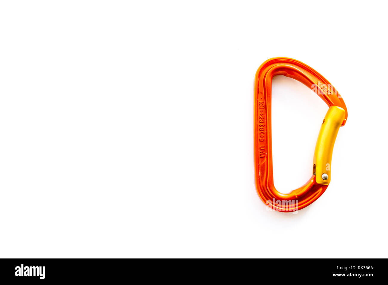 Orange solid bent gate carabiner for rope clipping, isolated on white background, with copy space. Basic climbing gear with axis strength ratings. Stock Photo