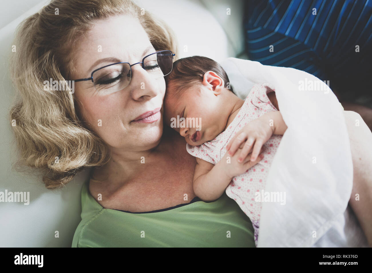 Beautiful newborn baby girl in grandmothers arms at home. Stock Photo